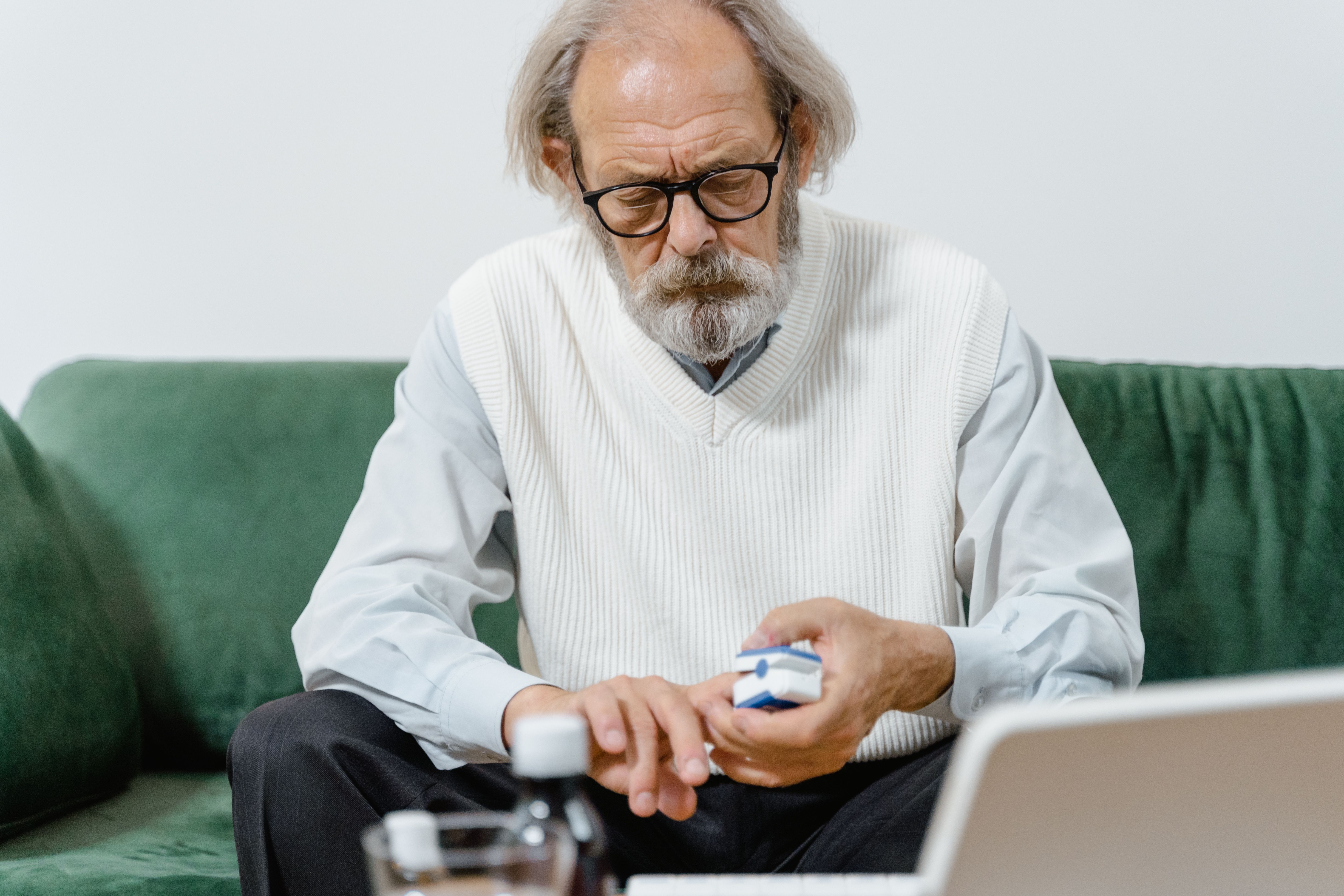 Older man examining his medication carefully at home